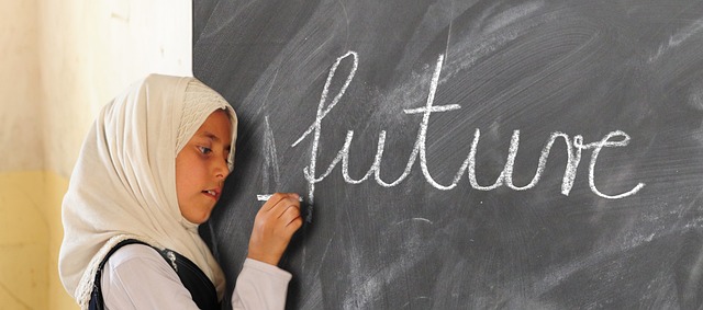 Girl in a hijab writing future on a blackboard