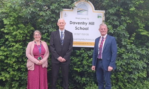 Headteacher Vicki Bond with WNC Coucillor Peter Matten and Stuart Andrew MP standing by the Daventry Hill School sign.